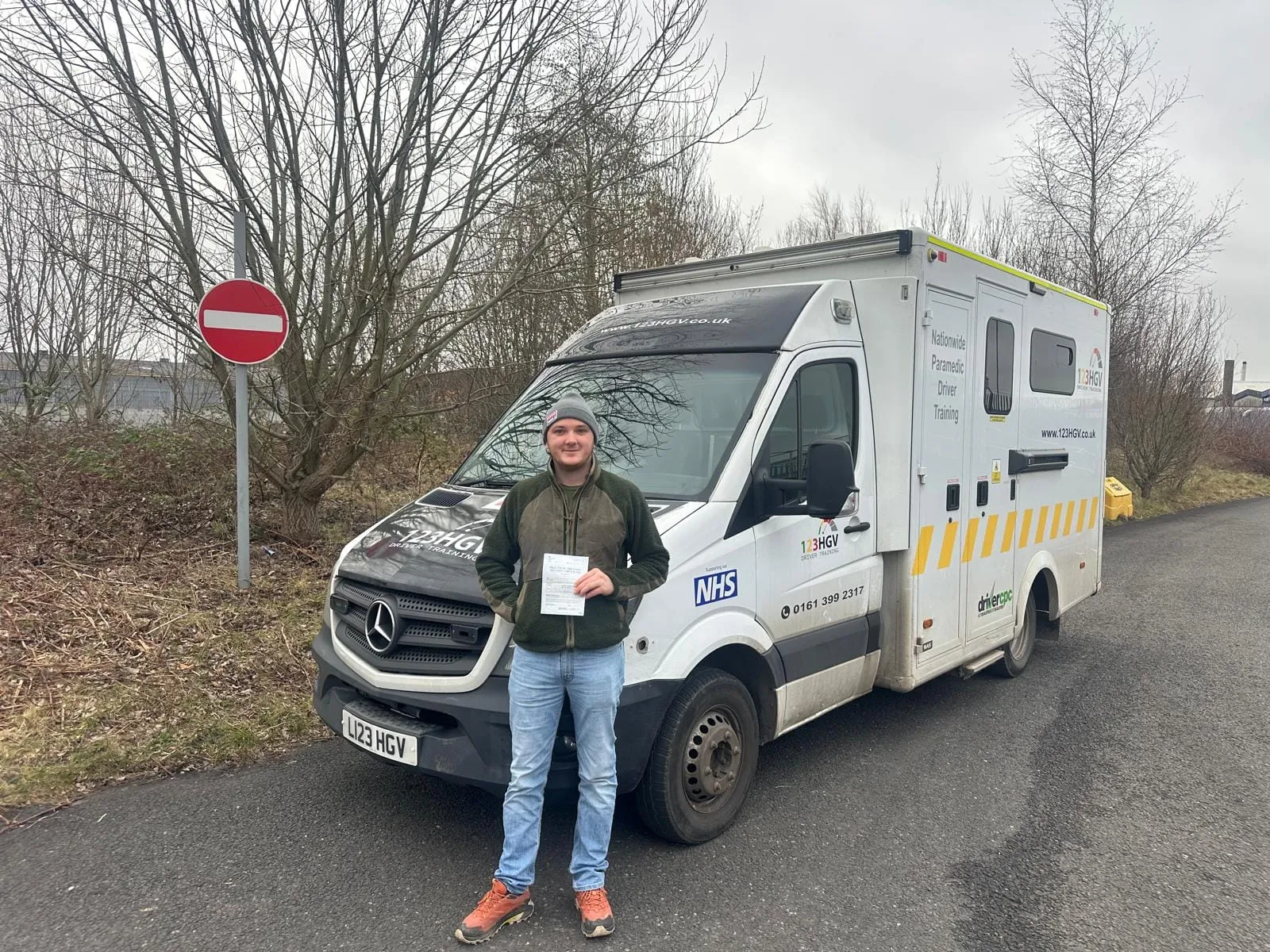 C1 learner holding a pass certificate by the ambulance training vehicle